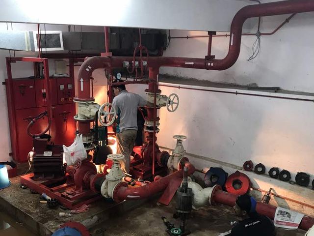 Technicians maintaining fire pump room pipework