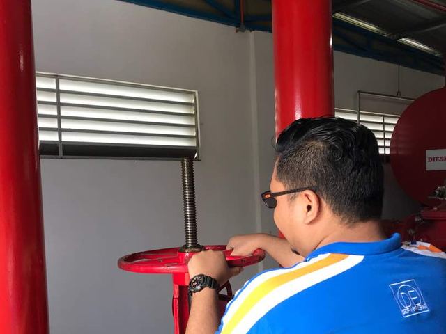 Technician operating a fire pump room control valve
