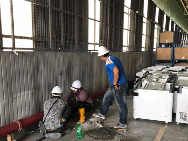 Technicians working on pipework inside an industrial warehouse