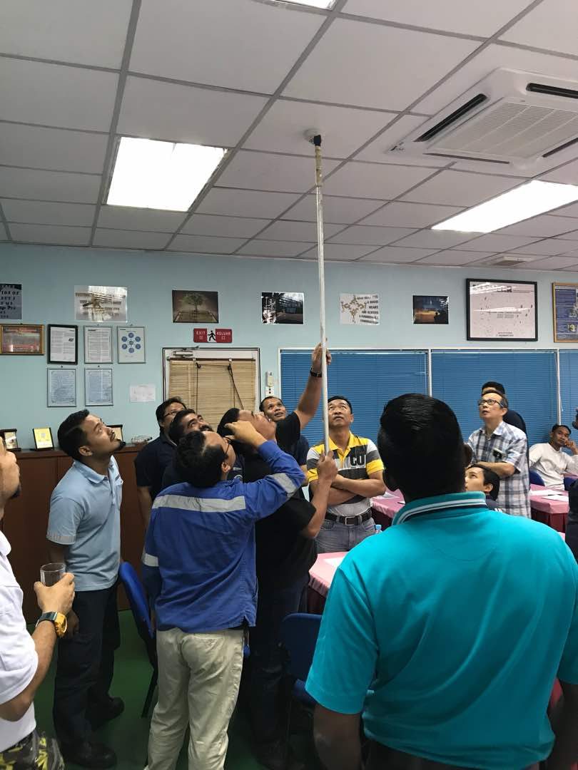 Testing a ceiling smoke detector during a fire alarm system check
