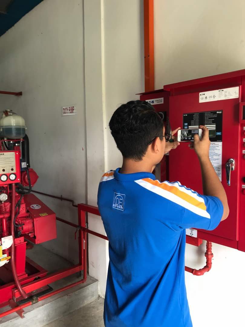 Technician documenting a fire pump controller panel for compliance records
